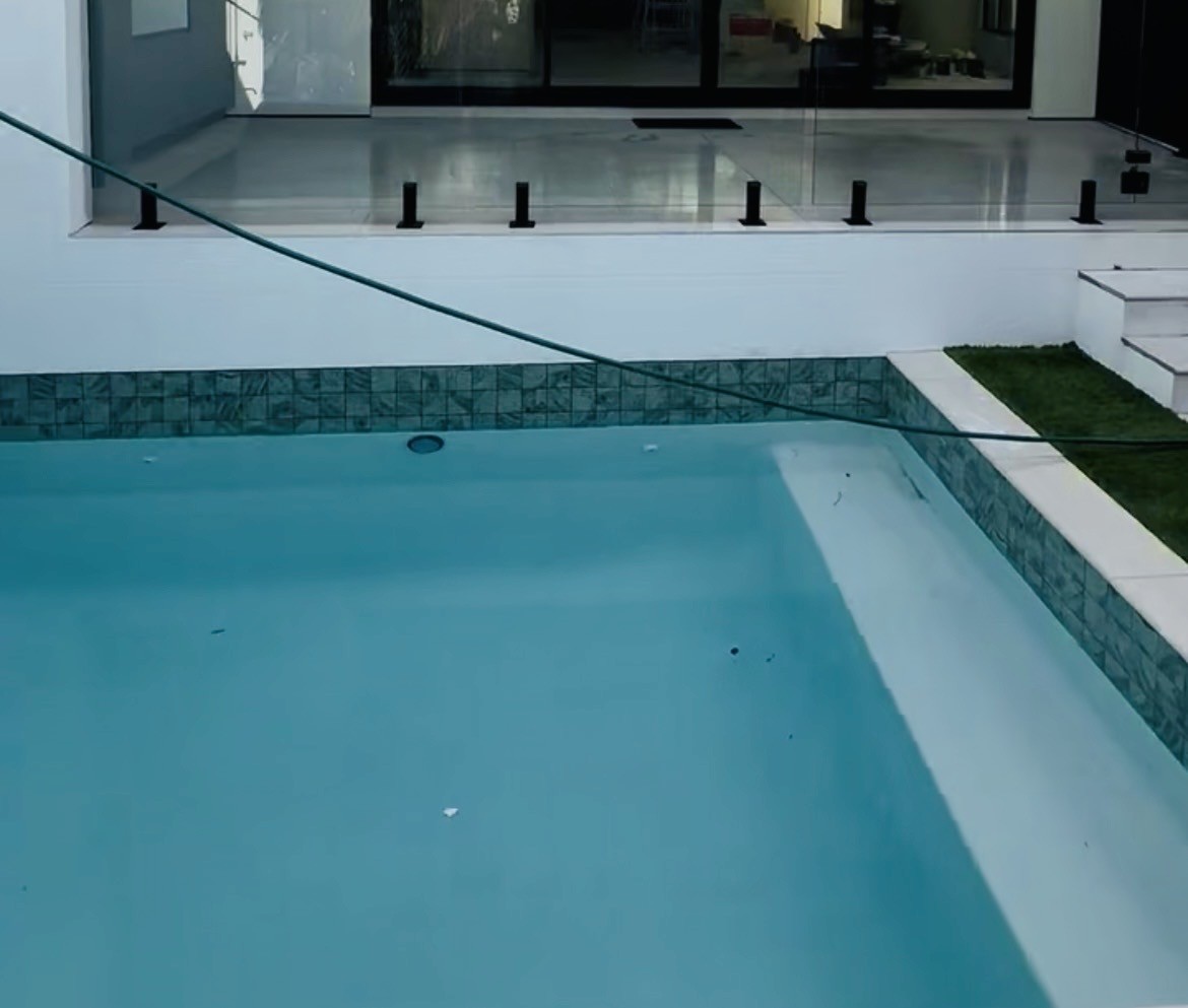 Frameless glass pool fence with black spigots beside a Gold Coast pool