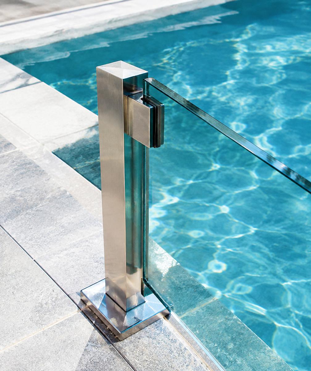 Glass pool fence beside a backyard pool